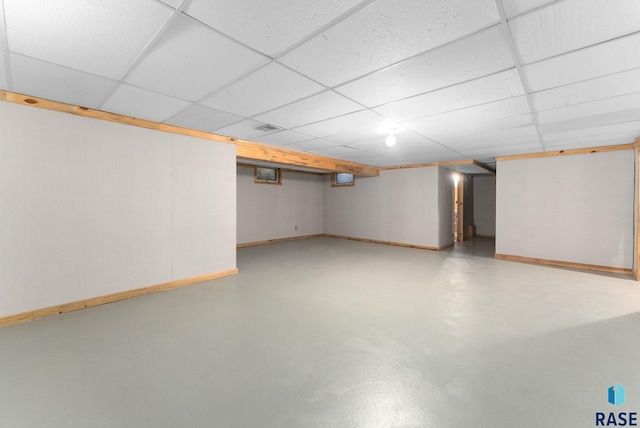 finished basement featuring baseboards, visible vents, and a paneled ceiling