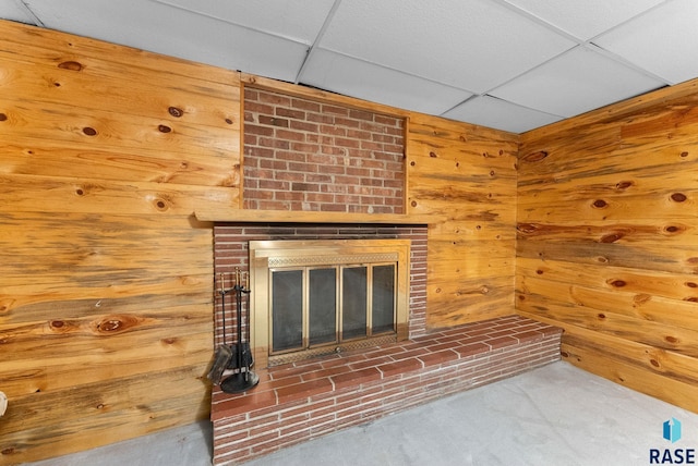 details with carpet floors, a fireplace, a drop ceiling, and wooden walls