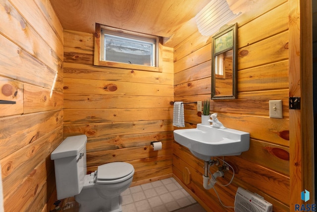half bath featuring tile patterned floors, wooden walls, and toilet
