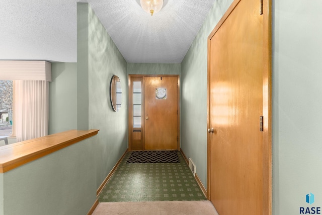 doorway with a textured ceiling, baseboards, and visible vents