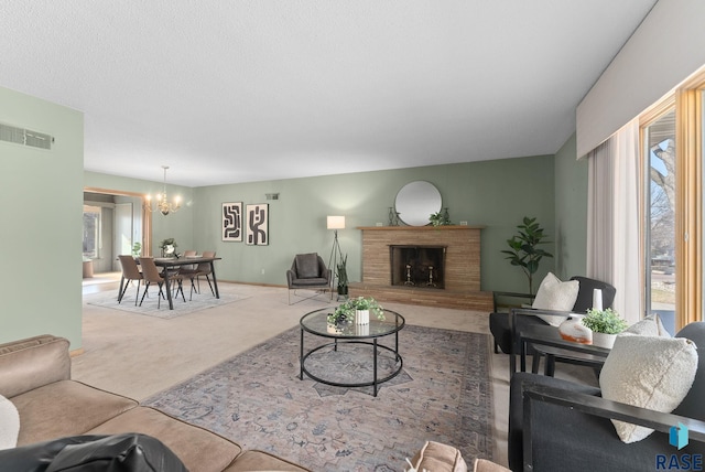 living area with visible vents, a chandelier, carpet, baseboards, and a fireplace