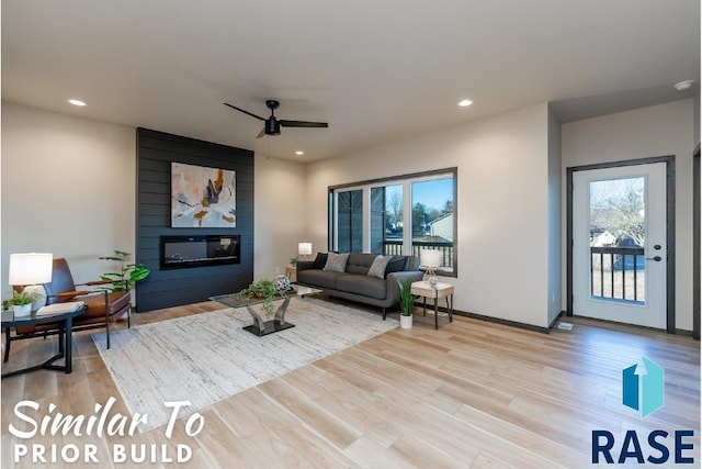 living area with recessed lighting, light wood-style floors, ceiling fan, and a large fireplace