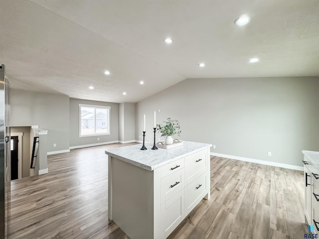 kitchen with baseboards, white cabinets, light wood-style floors, and a kitchen island
