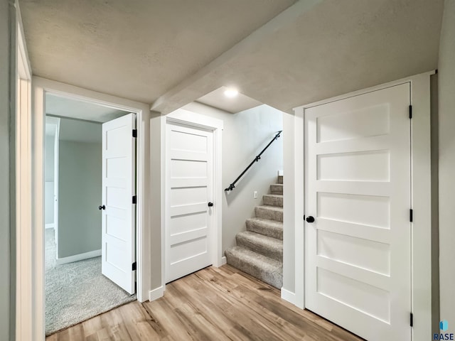 basement with baseboards, light wood-style floors, and stairs