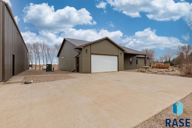view of property exterior featuring driveway, an attached garage, and metal roof