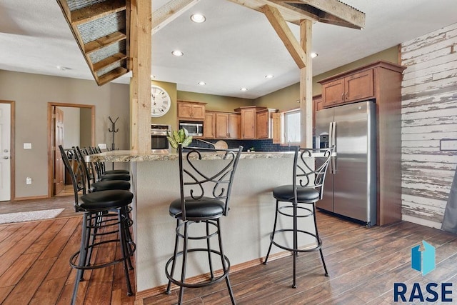 kitchen featuring a breakfast bar, dark wood finished floors, and appliances with stainless steel finishes