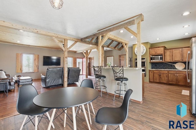 dining space with wood finished floors, recessed lighting, and beam ceiling