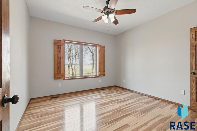 spare room with light wood finished floors, visible vents, and ceiling fan