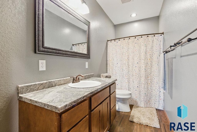 bathroom featuring toilet, curtained shower, vanity, wood finished floors, and visible vents