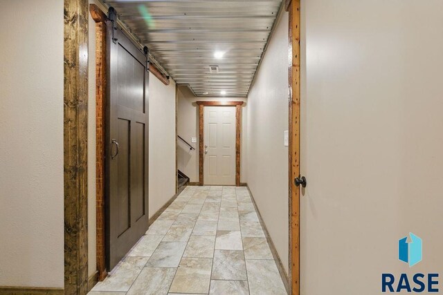 hallway with stairs, a barn door, wooden ceiling, and baseboards