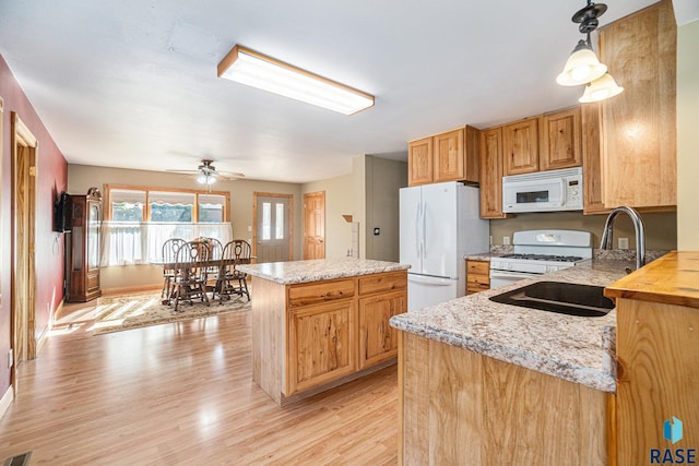kitchen with a sink, a center island, white appliances, light wood-style floors, and ceiling fan