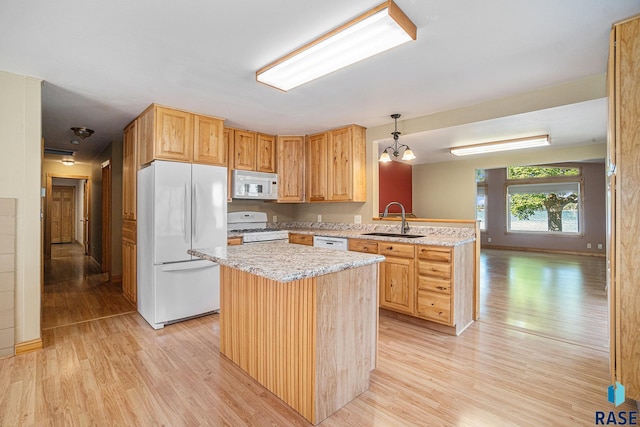 kitchen featuring light wood-type flooring, a sink, a peninsula, and white appliances