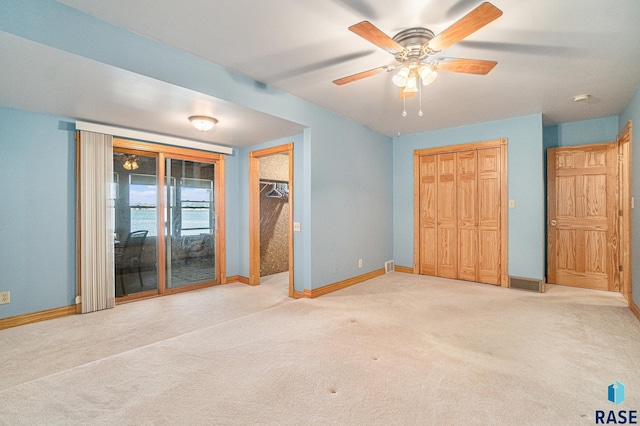 unfurnished bedroom featuring baseboards, carpet flooring, access to exterior, and a ceiling fan