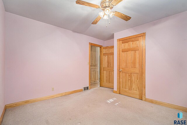 unfurnished bedroom featuring baseboards, ceiling fan, visible vents, and light carpet