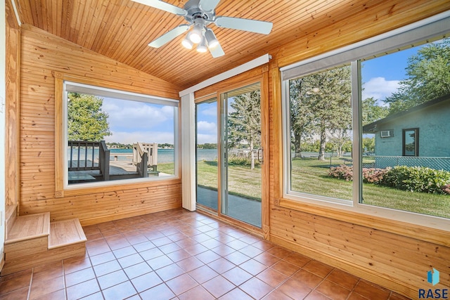 unfurnished sunroom featuring wood walls, tile patterned flooring, and plenty of natural light