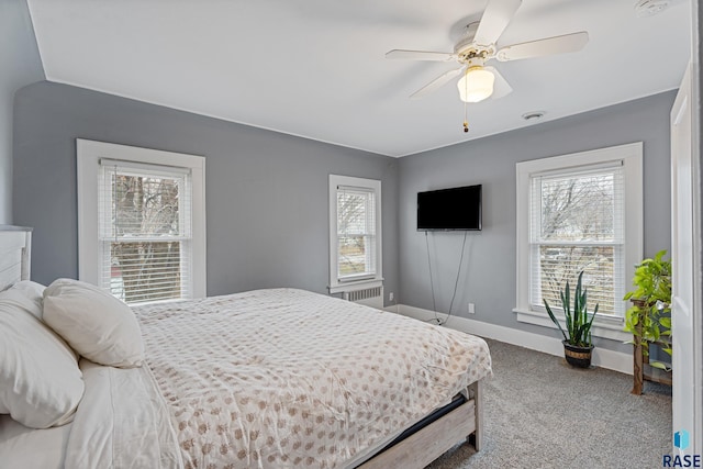 carpeted bedroom with baseboards, radiator, and ceiling fan