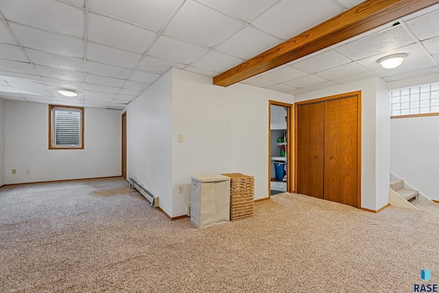 basement with baseboards, carpet floors, a paneled ceiling, and a baseboard radiator