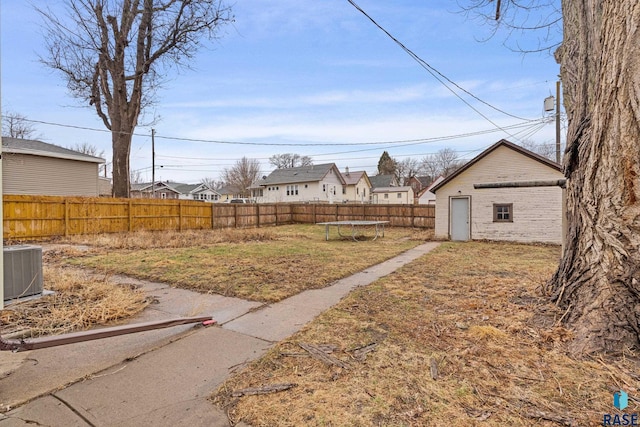 view of yard with a fenced backyard, a residential view, central AC, and a trampoline