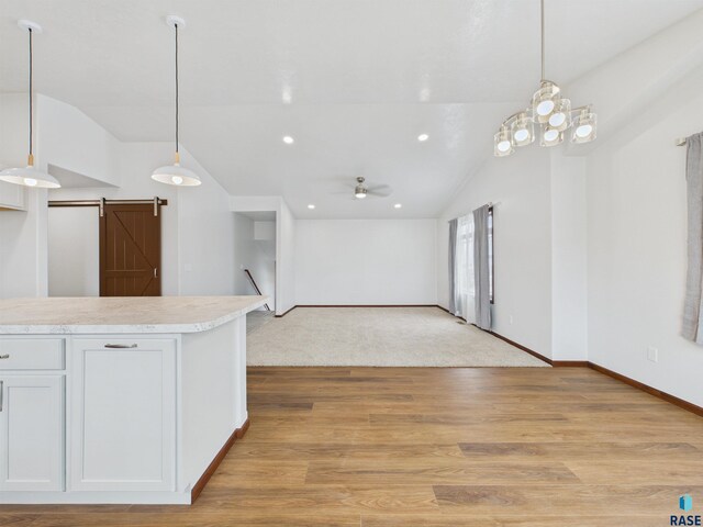 kitchen featuring light countertops, a barn door, lofted ceiling, light wood-style flooring, and ceiling fan