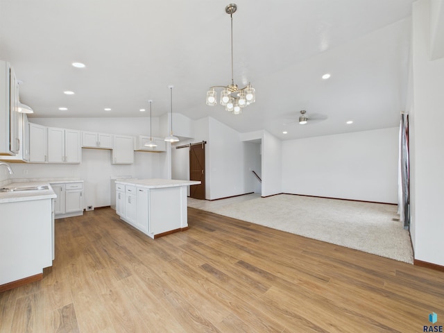 kitchen with light wood-style flooring, a sink, vaulted ceiling, and white cabinets