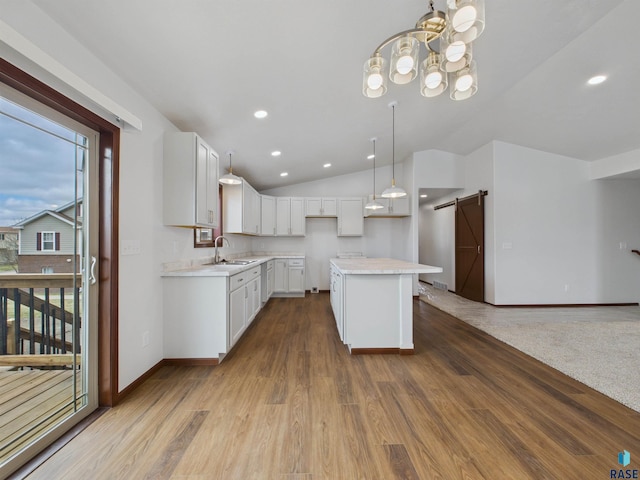 kitchen with vaulted ceiling, a barn door, light countertops, and a sink