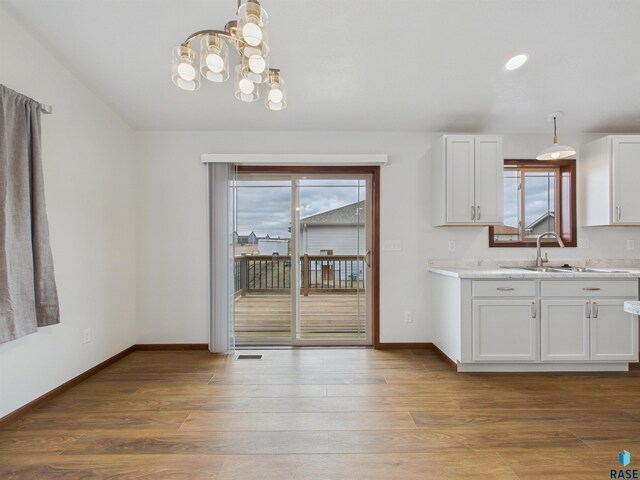 kitchen with baseboards, light countertops, wood finished floors, and a sink