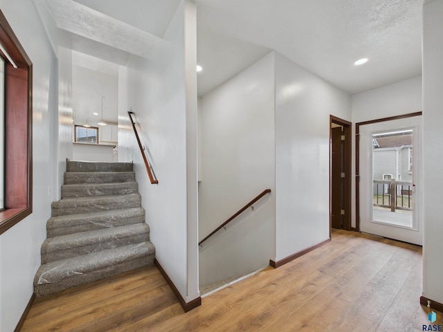 stairs with recessed lighting, baseboards, and wood finished floors