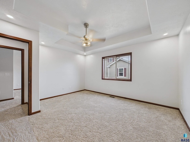 unfurnished room featuring baseboards, carpet flooring, a tray ceiling, and a ceiling fan