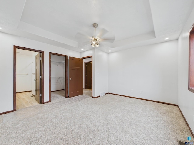 unfurnished bedroom featuring a tray ceiling, recessed lighting, and light carpet