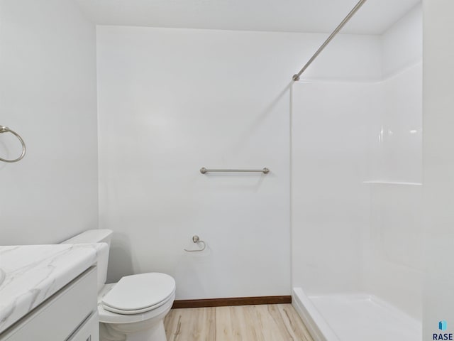 bathroom featuring walk in shower, baseboards, wood finished floors, toilet, and vanity