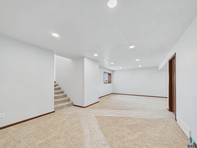 below grade area featuring stairway, light carpet, baseboards, visible vents, and recessed lighting