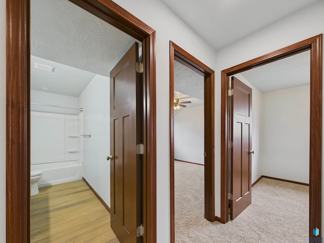 hall with baseboards, light colored carpet, and visible vents