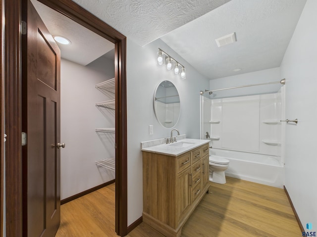 full bath with a textured ceiling, visible vents, wood finished floors, vanity, and bathing tub / shower combination
