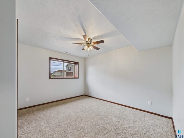unfurnished room with baseboards, ceiling fan, carpet, and a textured ceiling