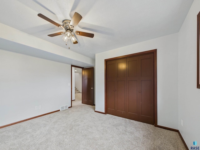 unfurnished bedroom featuring baseboards, visible vents, a closet, and light carpet