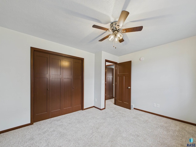 unfurnished bedroom with a ceiling fan, a closet, light carpet, and baseboards