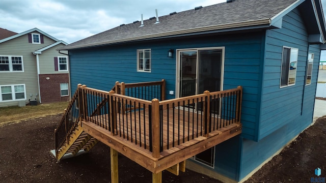 back of property with a shingled roof and a wooden deck