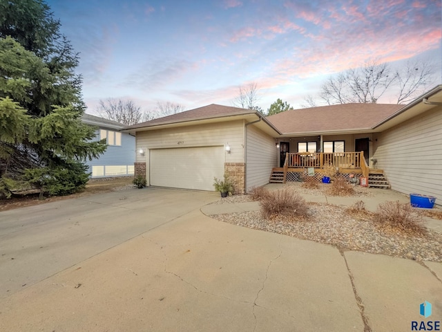single story home with driveway, an attached garage, and brick siding