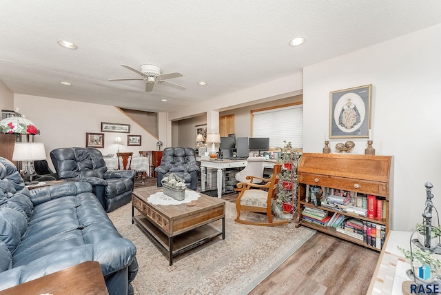 living area with a ceiling fan, recessed lighting, light wood-style flooring, and a textured ceiling