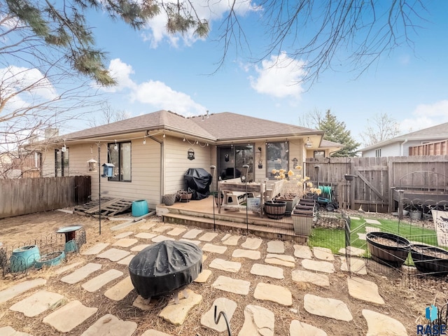 rear view of property featuring entry steps, a fenced backyard, roof with shingles, a fire pit, and a patio area