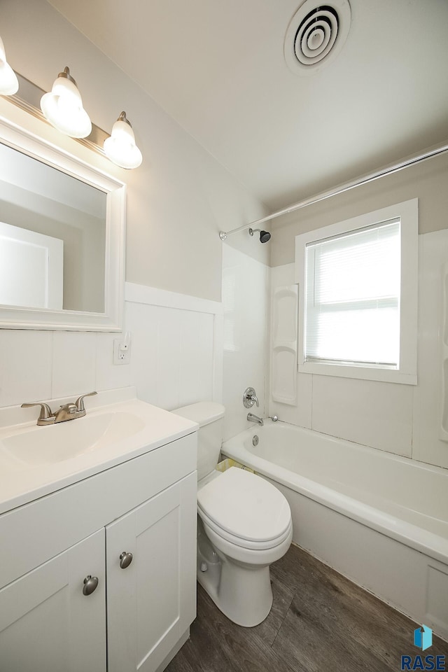 bathroom featuring tub / shower combination, vanity, visible vents, wood finished floors, and wainscoting