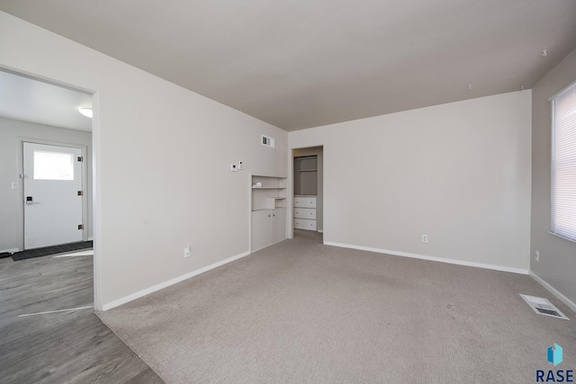 spare room with carpet flooring, baseboards, and visible vents