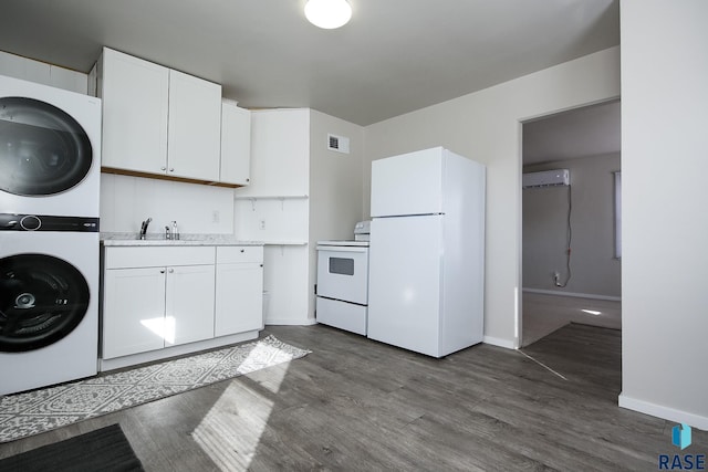 kitchen with white appliances, visible vents, stacked washer / dryer, a sink, and a wall mounted air conditioner