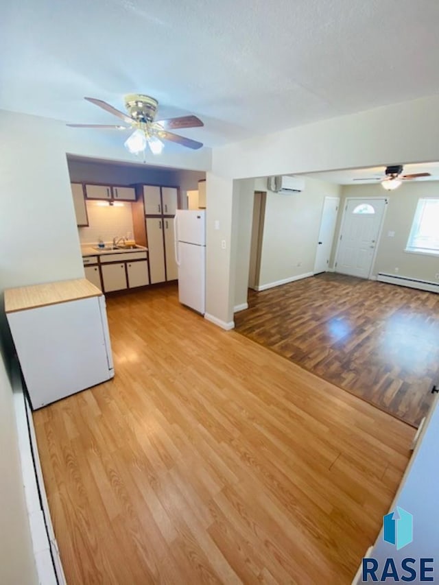 3016 E 20th St, Sioux Falls, SD 57103 - unfurnished living room featuring light wood-style floors, a baseboard heating unit, baseboards, and ceiling fan