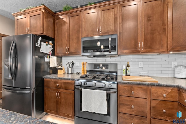 kitchen with brown cabinets, decorative backsplash, dark stone counters, and stainless steel appliances