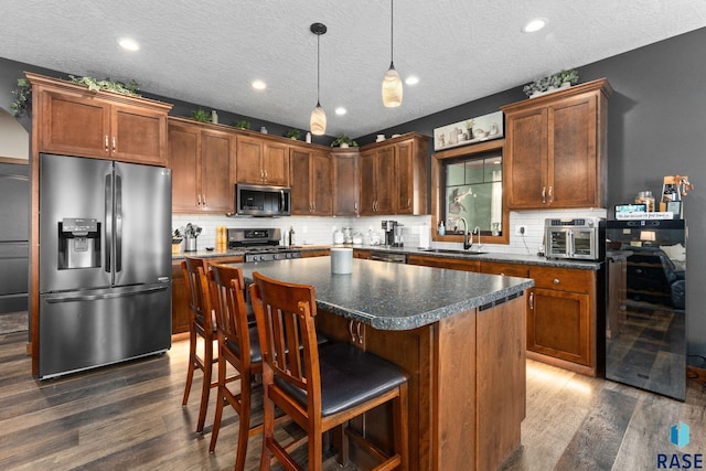 kitchen with a kitchen island, appliances with stainless steel finishes, dark wood-style flooring, a sink, and wine cooler