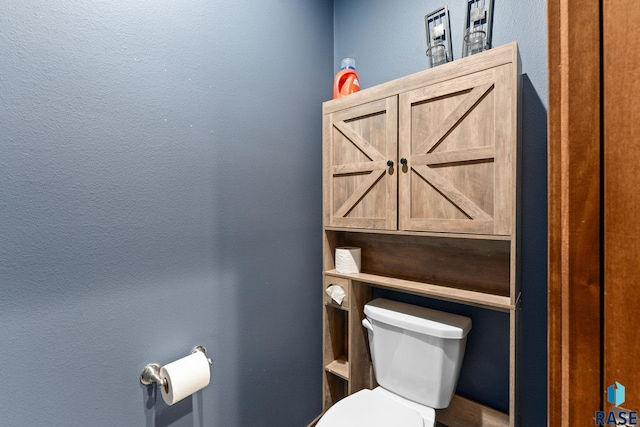 bathroom featuring toilet and a textured wall