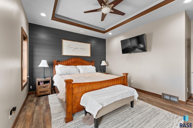 bedroom featuring visible vents, baseboards, a raised ceiling, recessed lighting, and wood finished floors