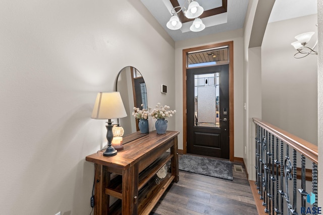 foyer featuring wood finished floors, an inviting chandelier, baseboards, and visible vents