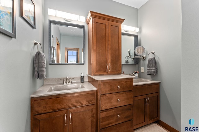 full bathroom with double vanity, a sink, and baseboards